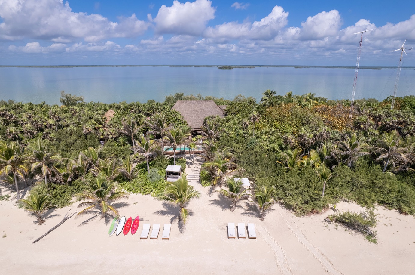 Casa Cantarena in Riviera Maya has a villa on the beach with steps leading to the sand. Lounge chairs and kayaks are laying there.