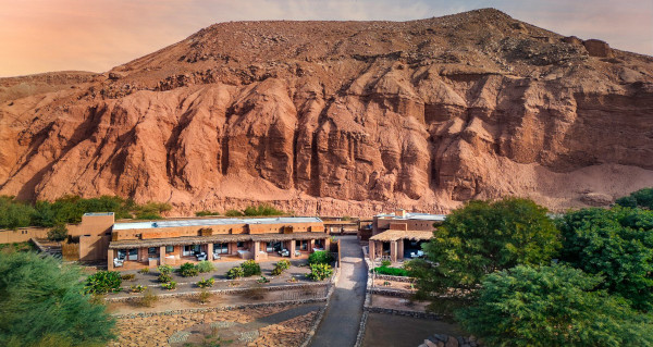 Aerial view of Nayara Alto in Chile. There's a group of rooms with a large desert mountain behind them.