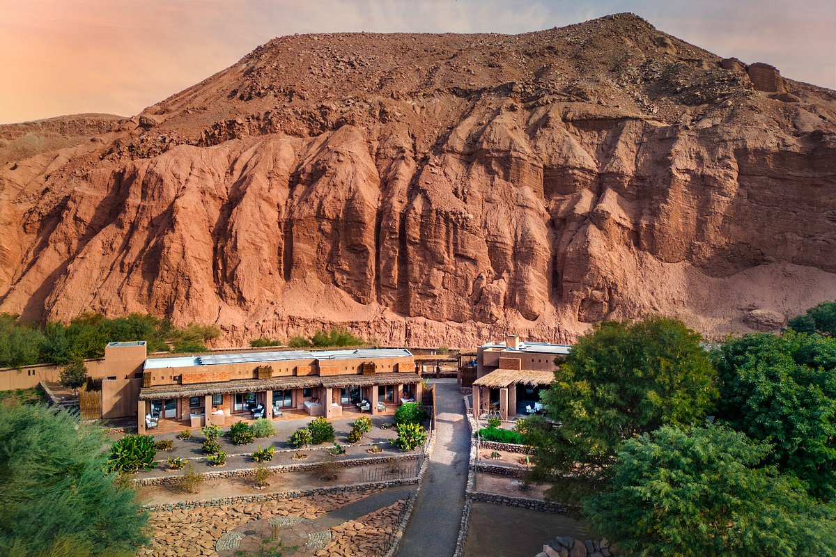 Aerial view of Nayara Alto in Chile. There's a group of rooms with a large desert mountain behind them. 